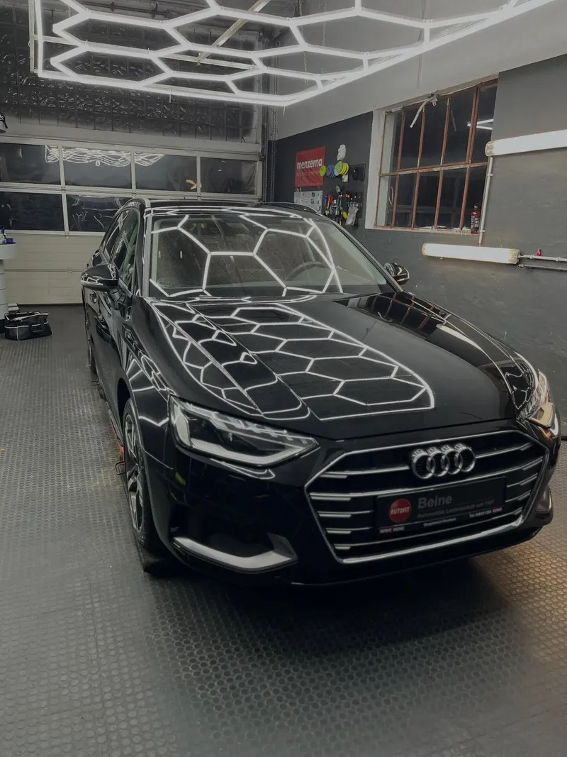 Schwarzer Audi A4 unter dem Wabenlicht der Werkstatt