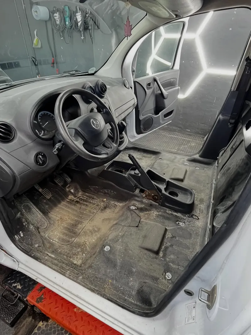 Stark verschmutzte Fahrerkabine eines Handwerkerfahrzeugs mit ausgebauten Sitzen