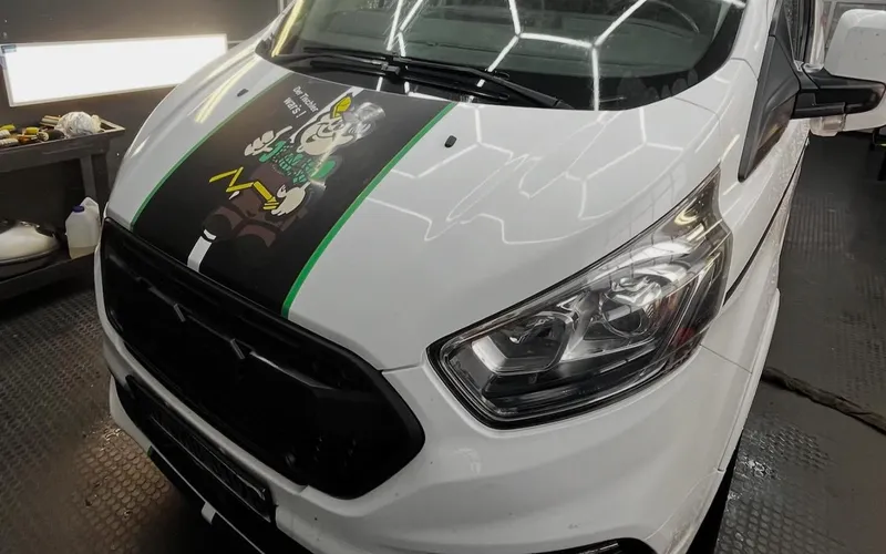 Weißer Ford Transit Custom unter dem Wabenlicht der Werkstatt